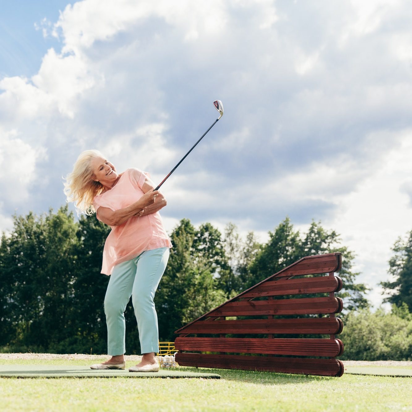 Senior active woman playing on a golf course.