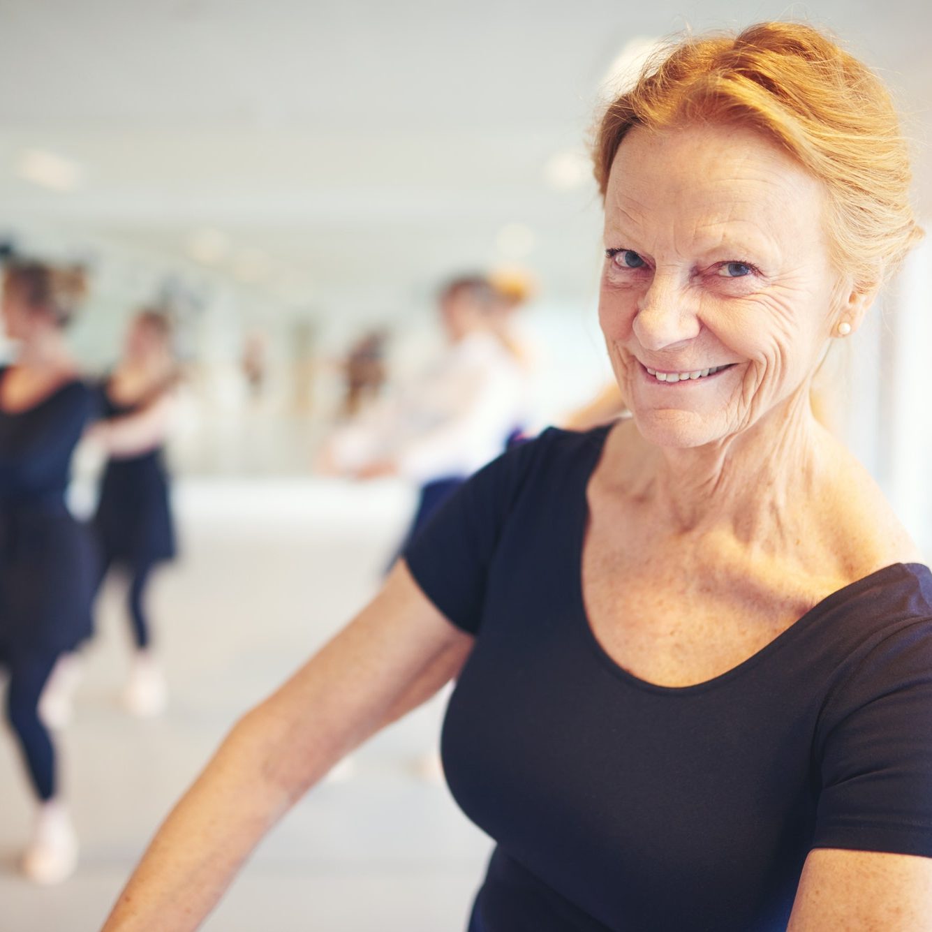 Active senior woman smiling and looking at camera performing ballet