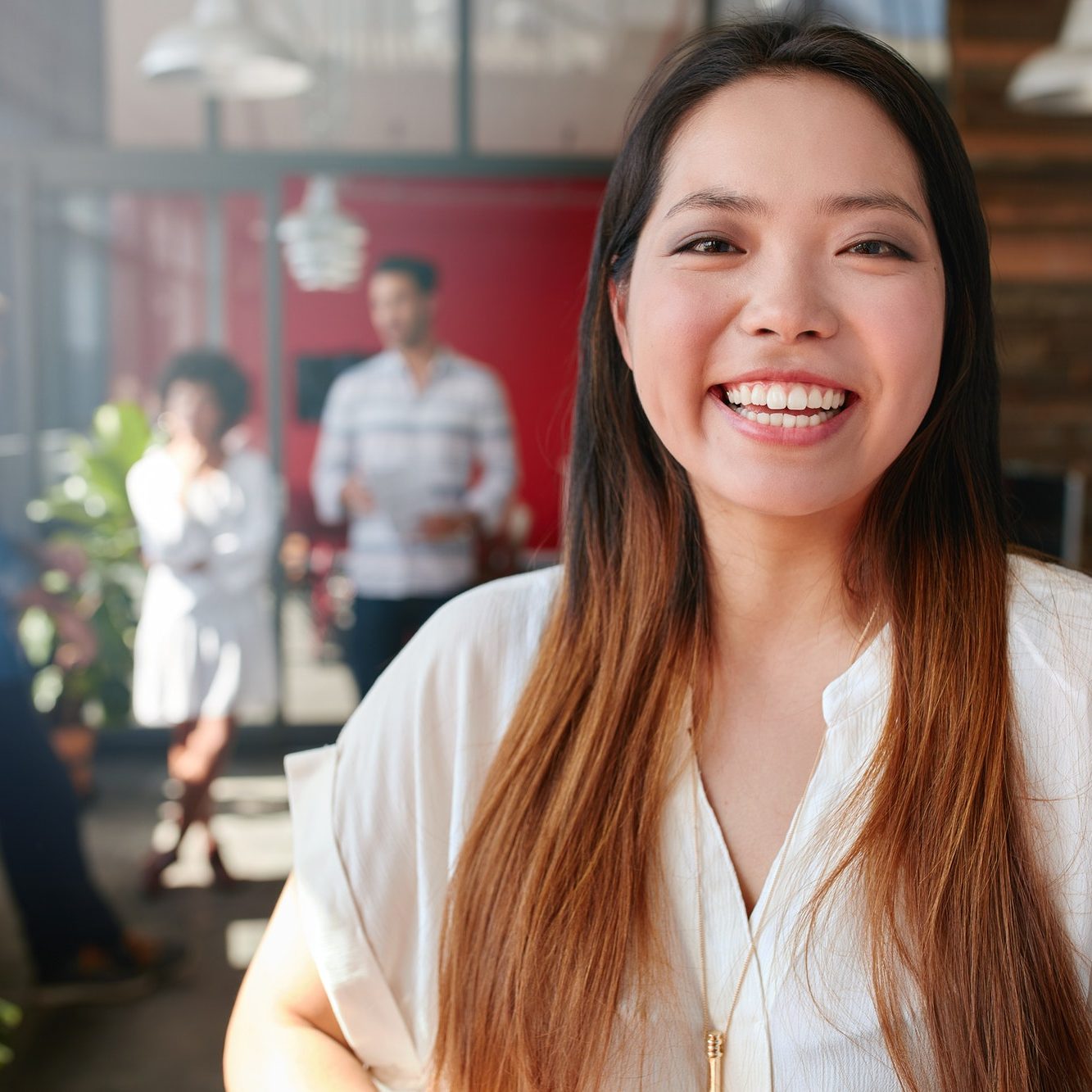 Cheerful young asian woman standing in office